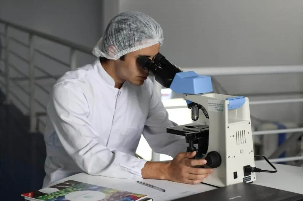 Lab technician analyzing mold sample under microscope